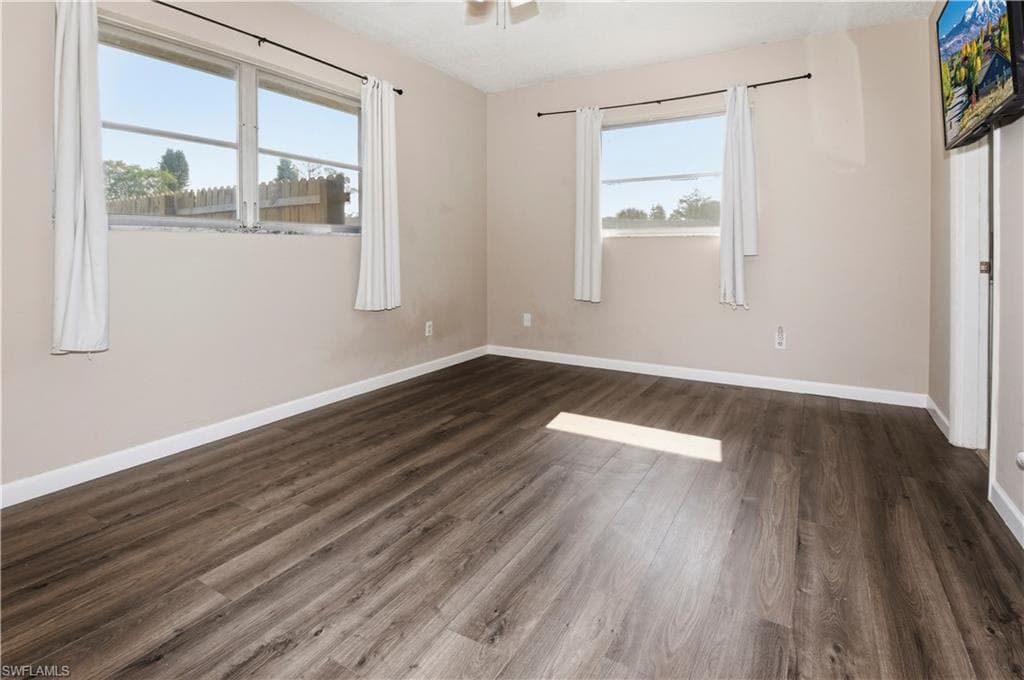 Unfurnished bedroom featuring dark wood-type flooring and multiple windows