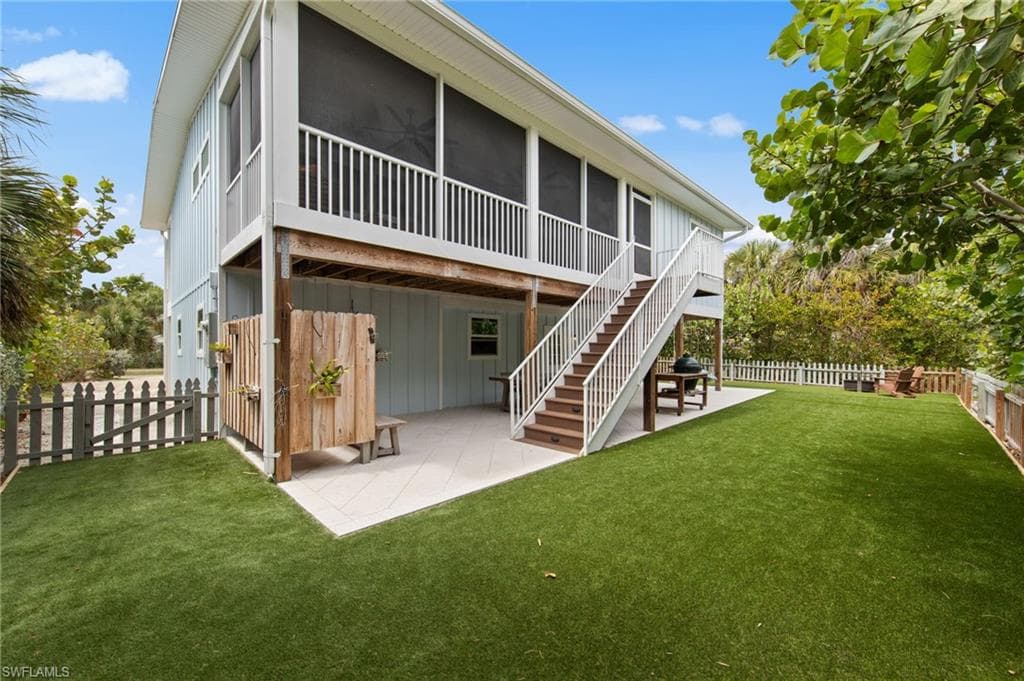 Rear view of property with a patio area, a sunroom, a fenced backyard, and board and batten siding