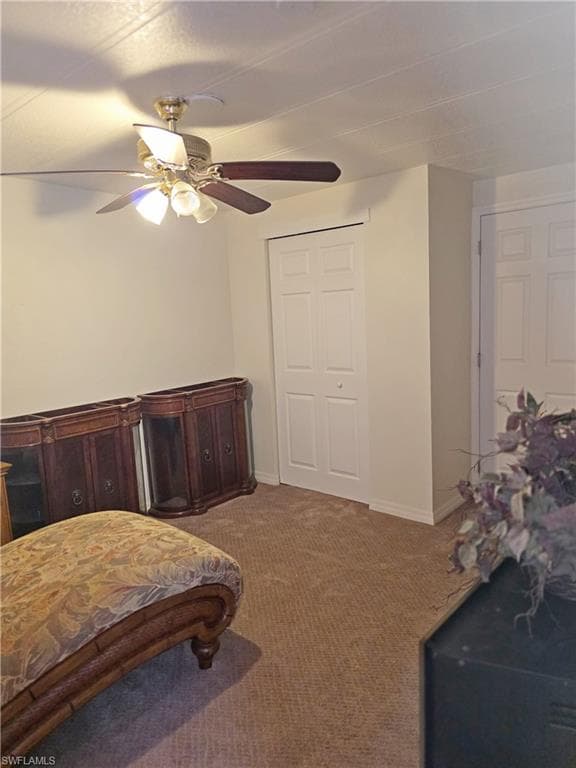 Bedroom featuring dark colored carpet, ceiling fan, and a closet