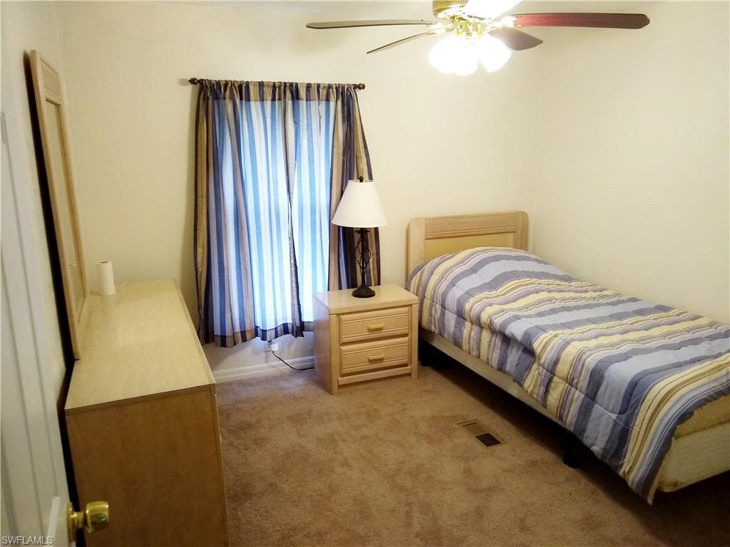 Bedroom with light colored carpet and a ceiling fan