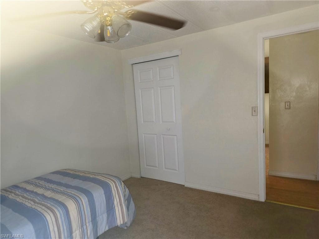 Bedroom featuring light colored carpet, a ceiling fan, and a closet