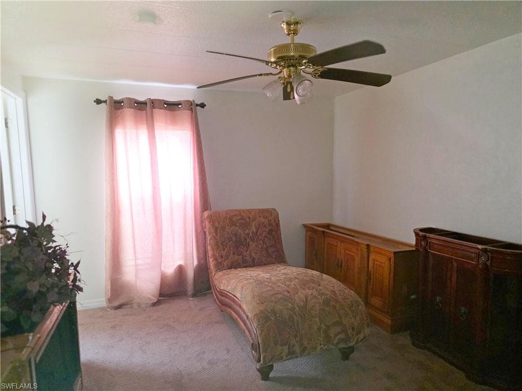 Sitting room featuring light colored carpet and a ceiling fan