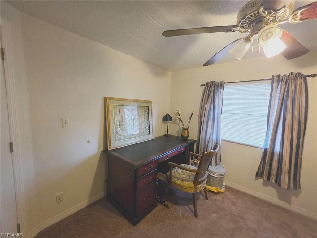 Home office with ceiling fan and dark carpet
