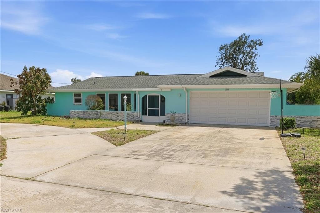 Ranch-style home with driveway, stucco siding, a garage, and a front yard