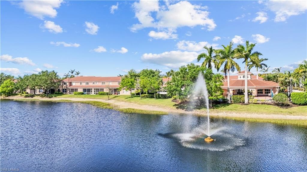 The property features waterfront views with a fountain, surrounded by mature palm trees and lush landscaping