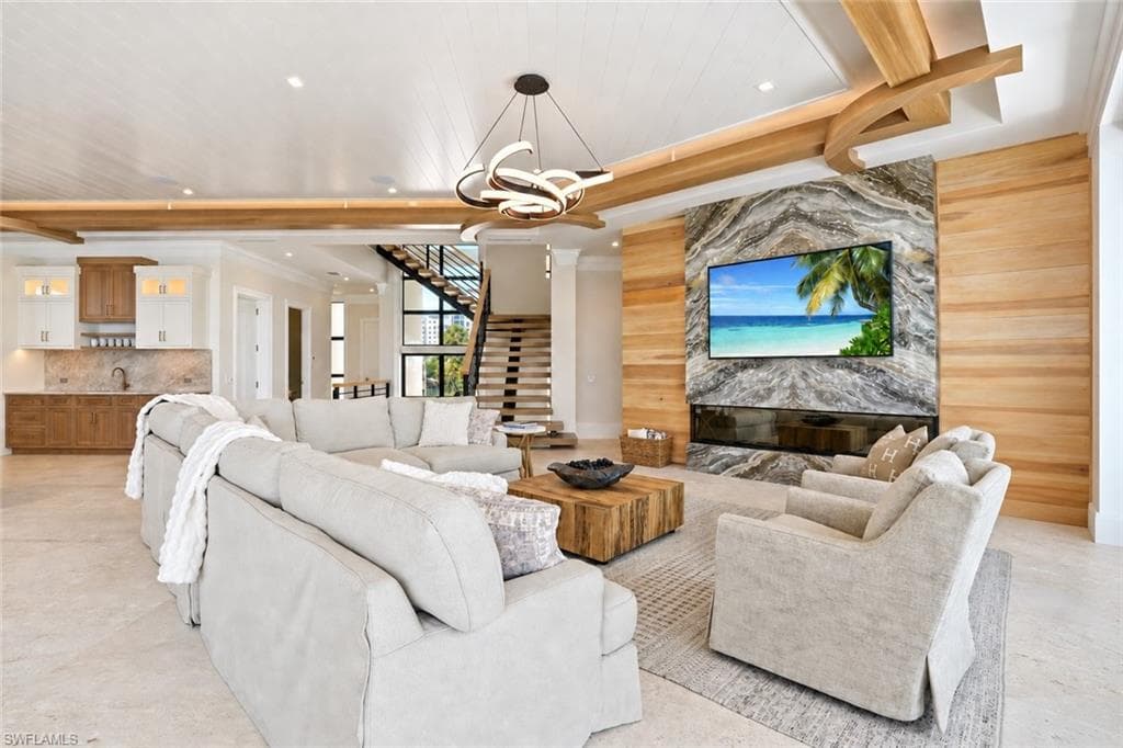 Expansive open-concept living area showcasing soaring wood beam ceilings, recessed lighting, and a contemporary pendant fixture - Virtually Edited Image