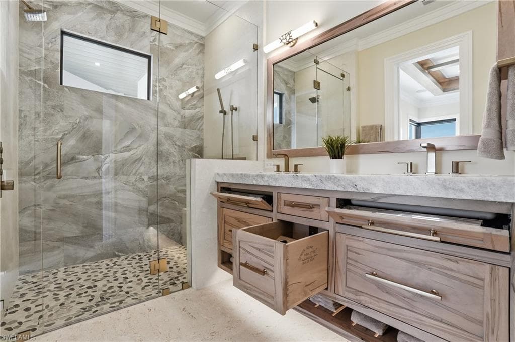 Full bathroom with ornamental molding, double vanity, and a marble finish shower - Virtually Edited Image