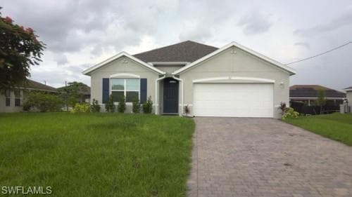 Ranch-style house featuring a front yard, an attached garage, stucco siding, and decorative driveway