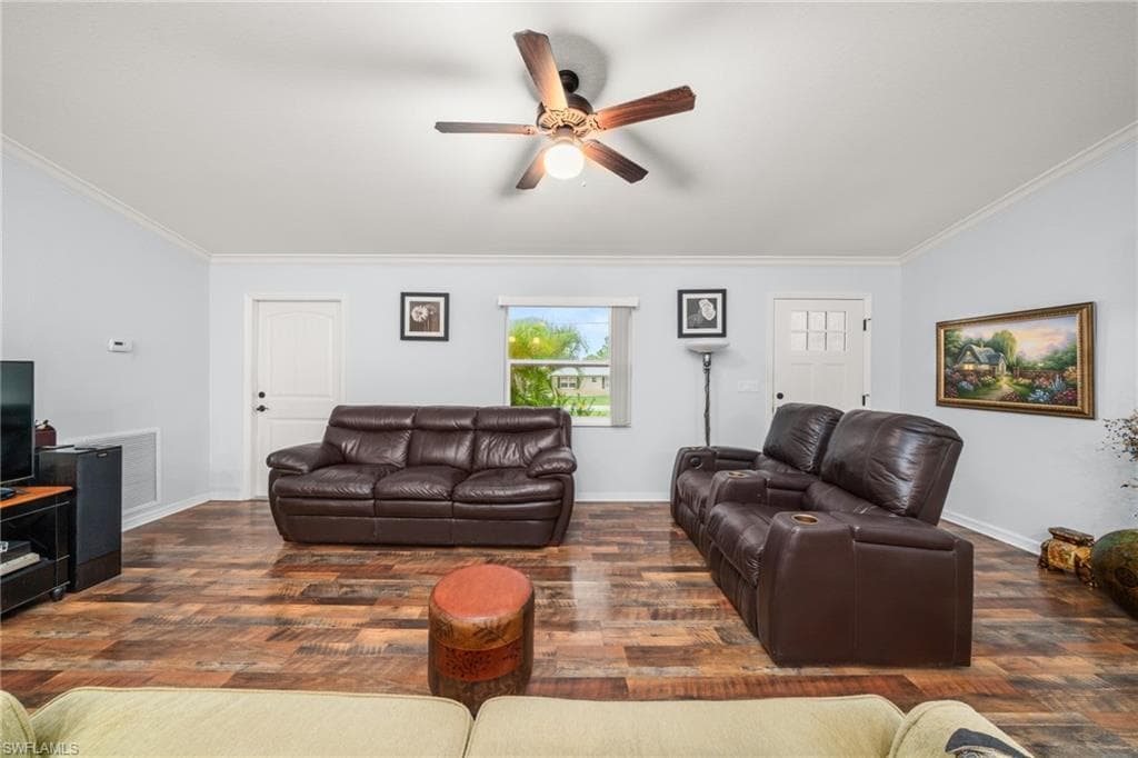 Living area featuring ornamental molding, a ceiling fan, and dark wood-style flooring
