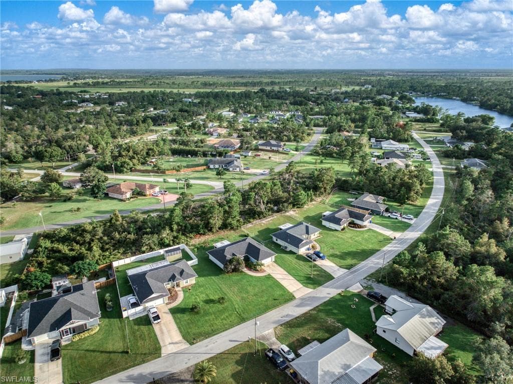 Aerial view of property and surrounding area featuring nearby suburban area and a nearby body of water
