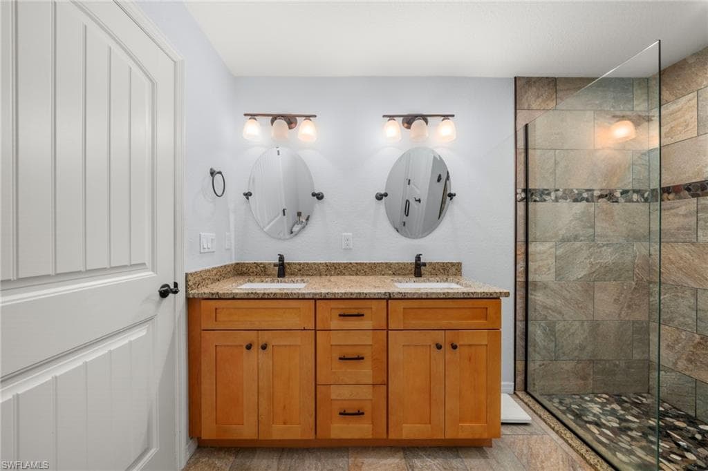 Full bath featuring a shower stall and double vanity