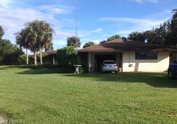 View of side of property with a lawn, an attached garage, and stucco siding