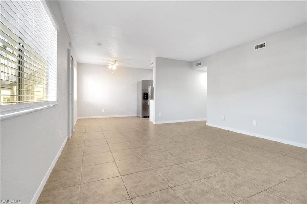 Unfurnished room featuring light tile patterned floors, visible vents, baseboards, and a ceiling fan
