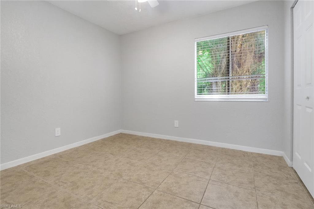 Spare room featuring baseboards, light tile patterned flooring, and a ceiling fan