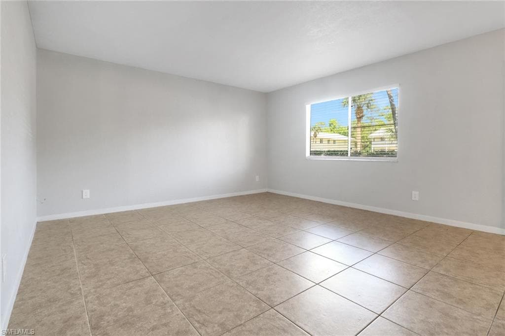 Spare room featuring tile patterned floors and baseboards