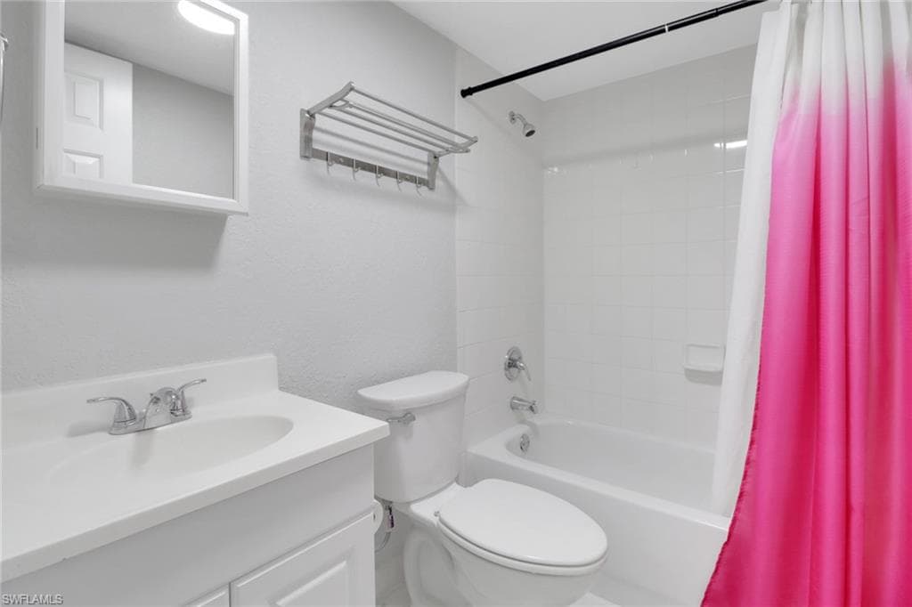 Bathroom with vanity, toilet, and shower / tub combo with curtain