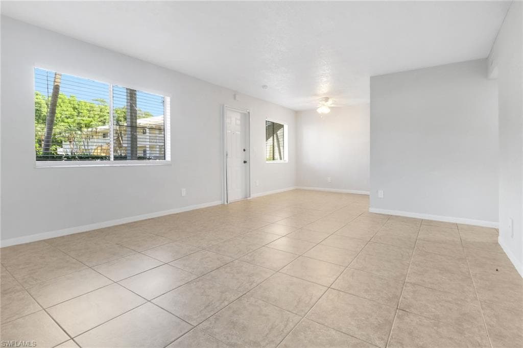 Spare room with light tile patterned floors, ceiling fan, and baseboards