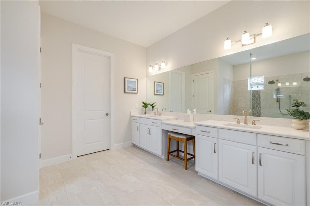 Full bath with double vanity, two vanities, a stall shower, and light tile patterned floors
