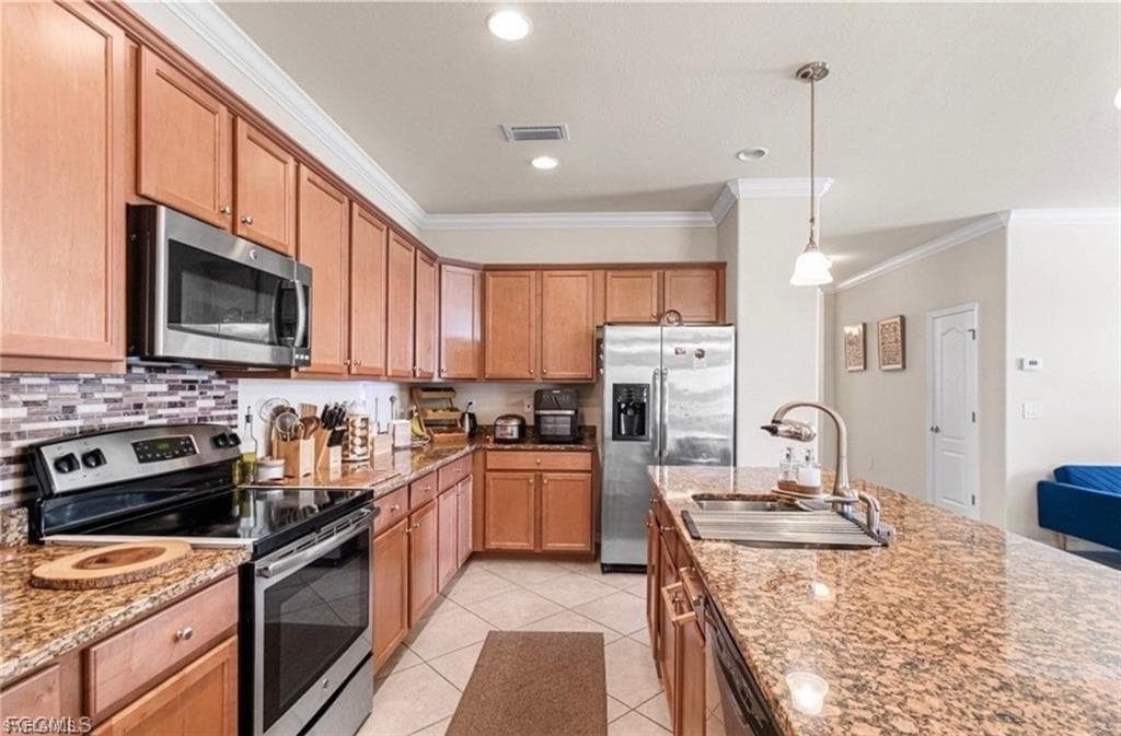 Kitchen featuring stainless steel appliances, ornamental molding, light stone countertops, decorative light fixtures, and light tile patterned floors
