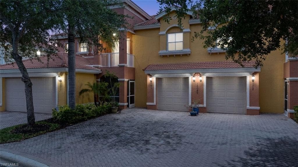 Mediterranean / spanish home featuring decorative driveway, stucco siding, a tiled roof, and an attached garage