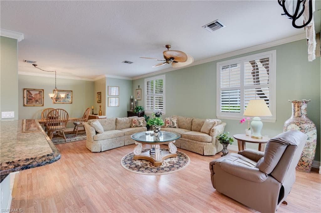 Living room featuring crown molding, a ceiling fan, light wood-style flooring, and hanging lights