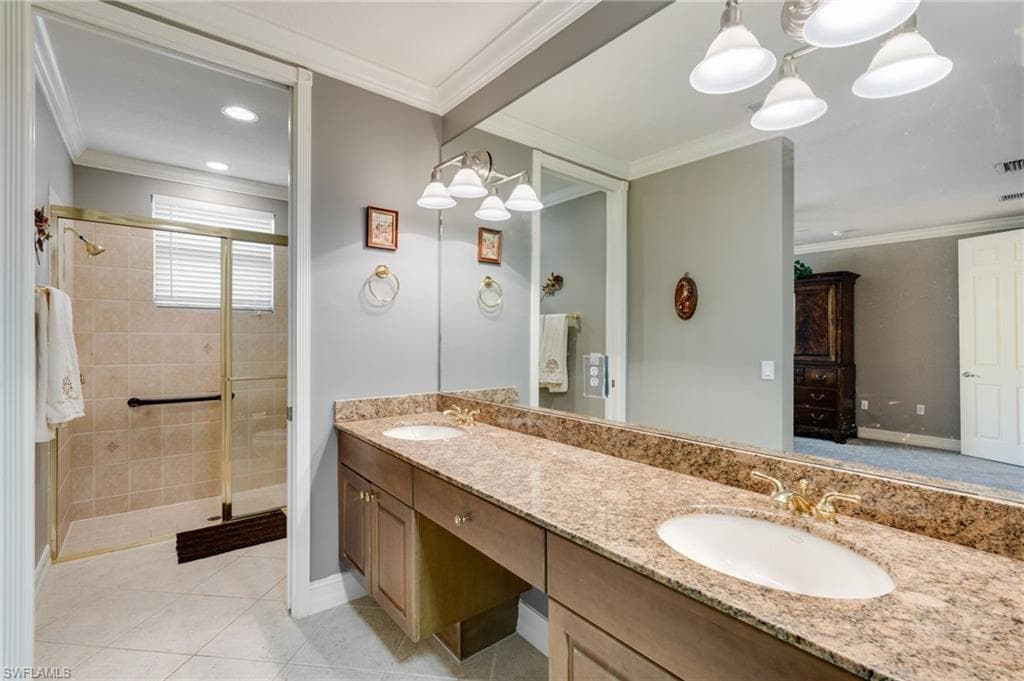 Full bathroom featuring double vanity, ornamental molding, a shower stall, light tile patterned floors, and recessed lighting