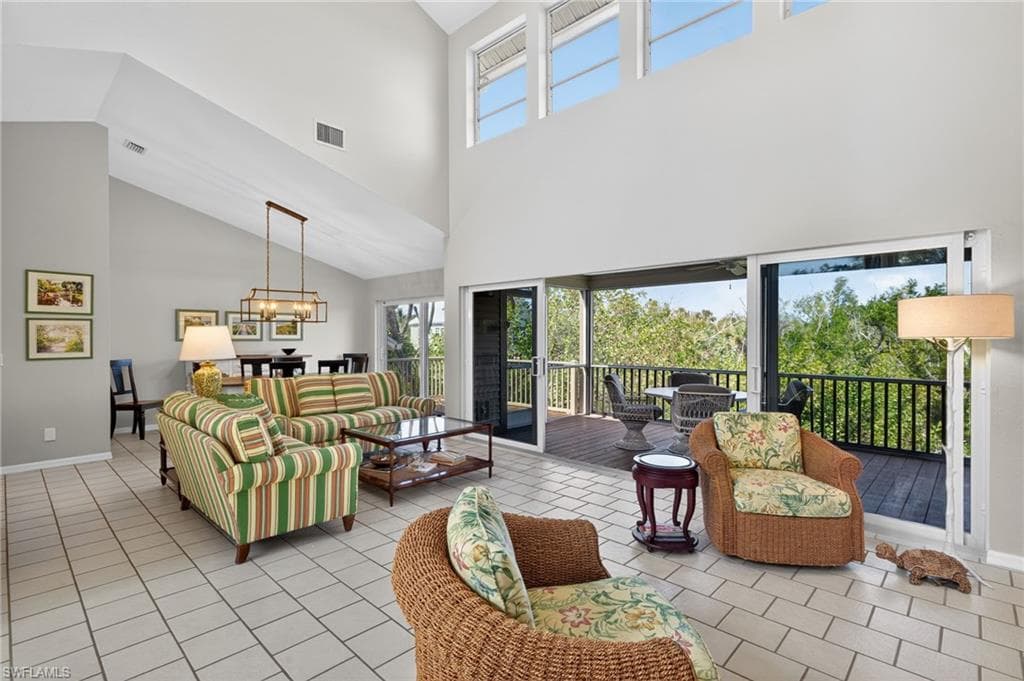 Living area featuring a high ceiling, suspended lighting, and light tile patterned floors