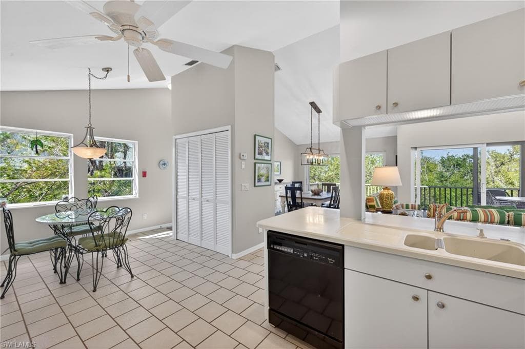 Kitchen featuring light countertops, hanging light fixtures, black dishwasher, lofted ceiling, and a ceiling fan