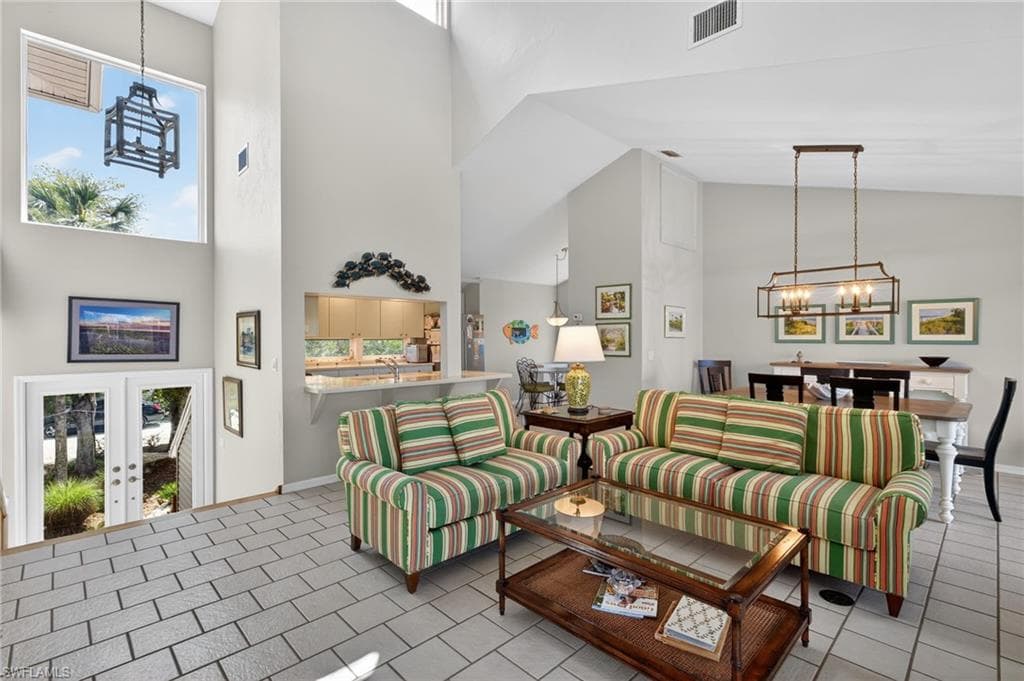 Living area featuring a chandelier, a high ceiling, and french doors
