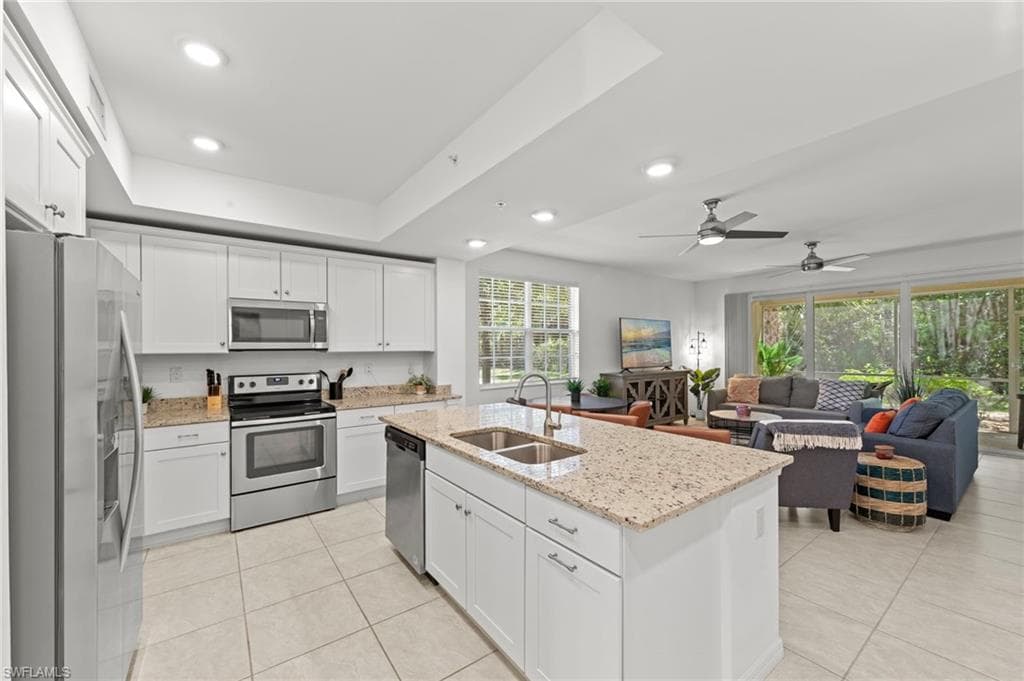 The kitchen features white cabinetry, stainless steel appliances, and a granite-topped island with an integrated sink