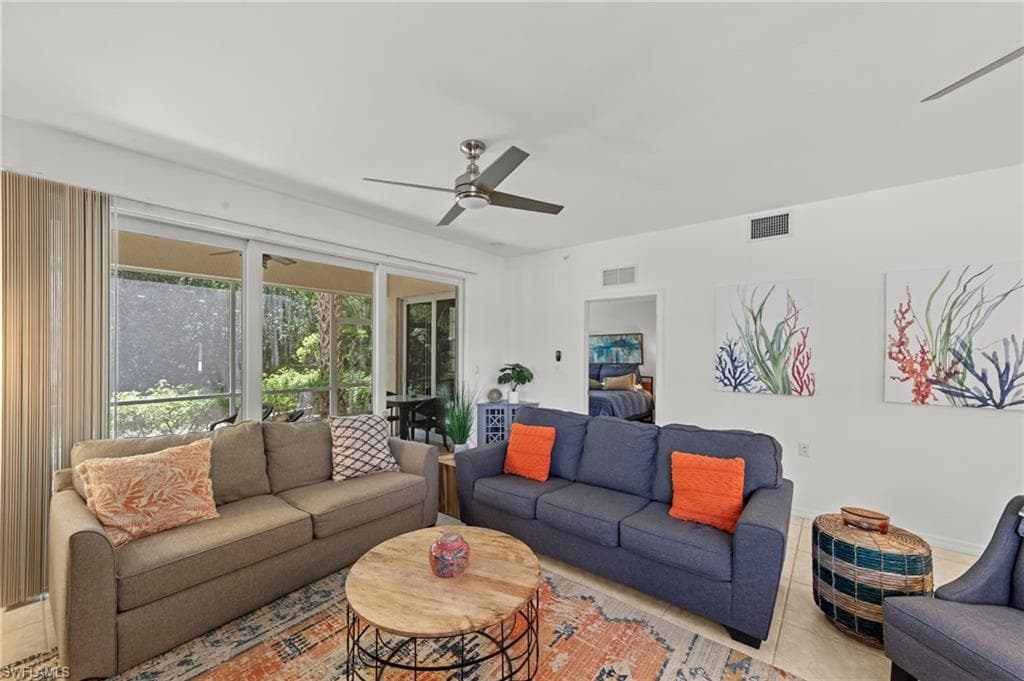 The living area features bright white walls, a ceiling fan, and large sliding glass doors leading to a screened outdoor space
