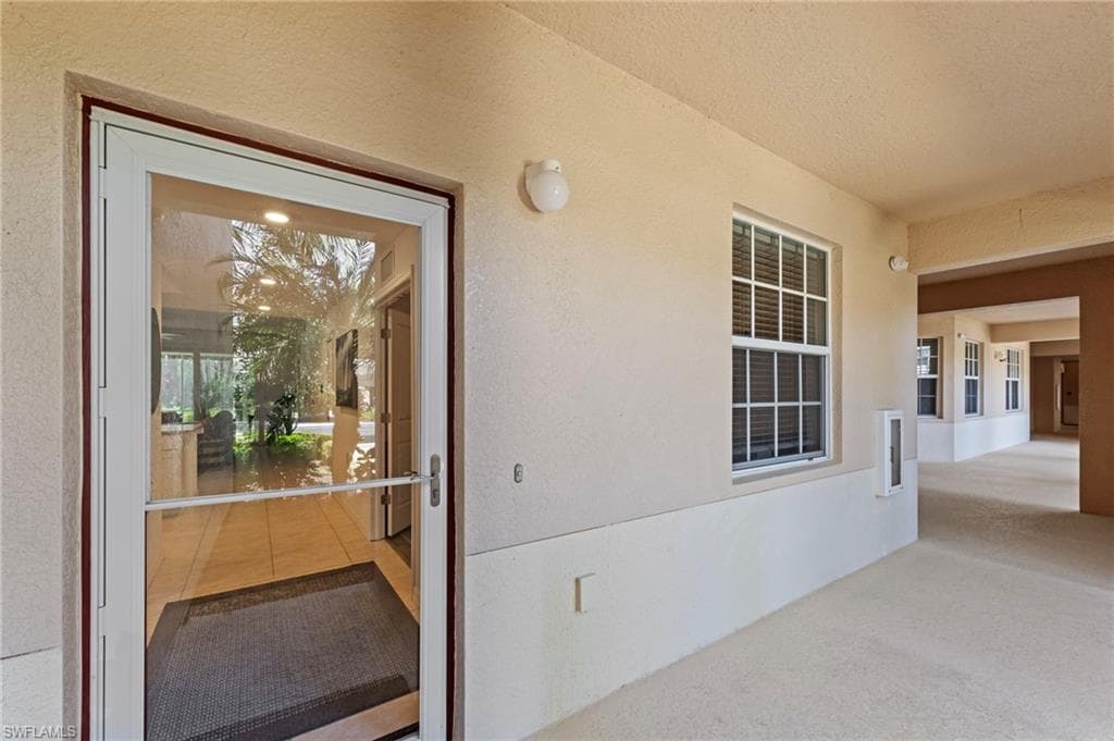 Entryway featuring a glass storm door, a window with blinds, and light-colored exterior walls