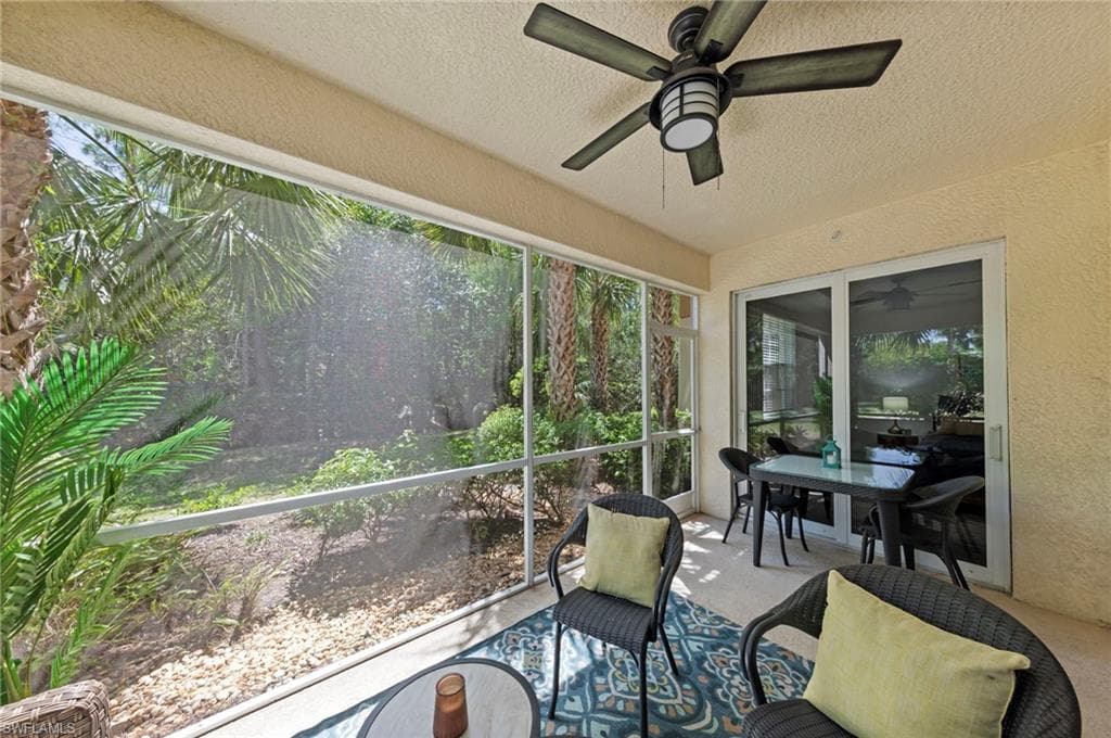 The property features a screened-in patio with a ceiling fan, offering views of surrounding palm trees and greenery