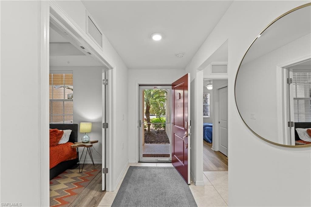 Entryway featuring a red front door, tiled flooring, and a round wall mirror