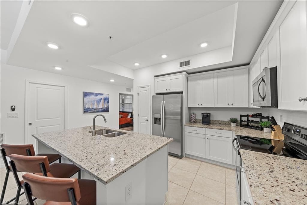 The kitchen features white cabinetry, granite countertops, tile flooring, and recessed lighting