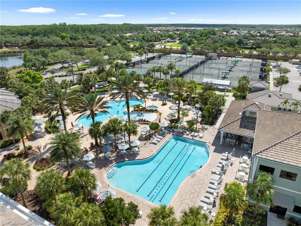 Aerial view showcasing the community amenities, including two swimming pools, tennis courts, and lush landscaping with palm trees