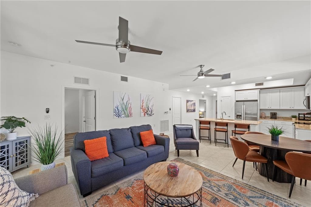 Open-concept living area featuring a kitchen with white cabinetry and stainless steel appliances, a dining area, and living room