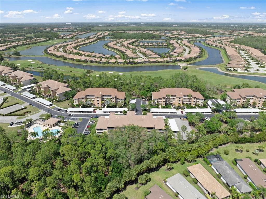 Aerial view showcasing the community with residential buildings, a swimming pool, and extensive green spaces
