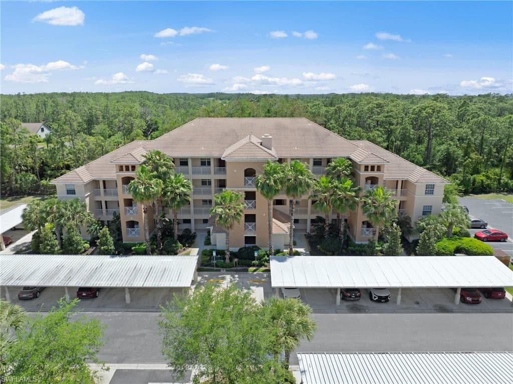 This property features a multi-story building with a tiled roof, surrounded by mature palm trees and lush green foliage