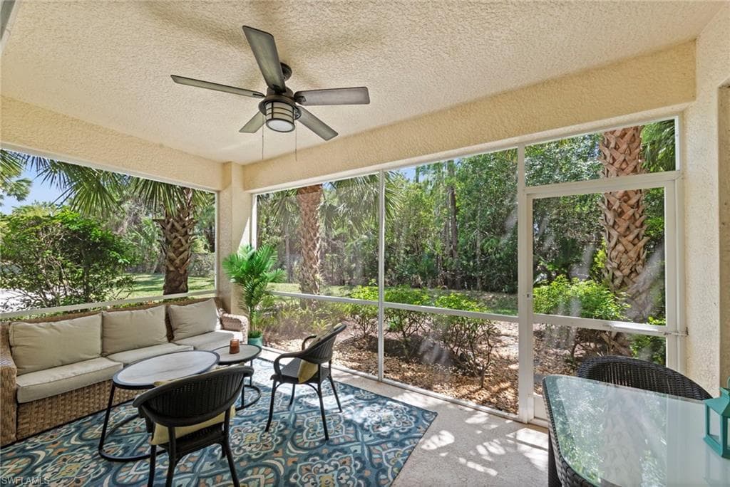 Screened patio with a ceiling fan and views of lush greenery