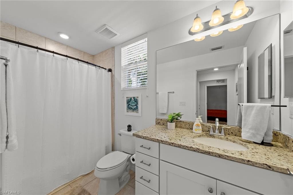 Bathroom with a white vanity featuring a granite countertop, an integrated sink, and chrome fixtures