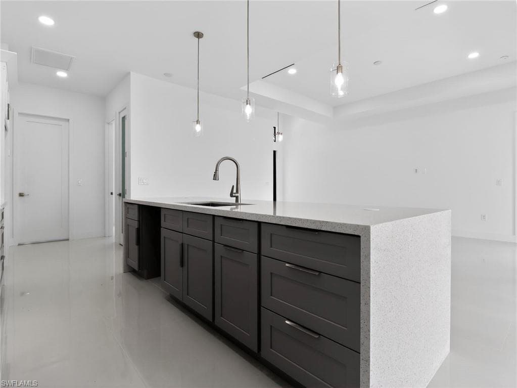 Spacious kitchen featuring a large island with dark cabinetry, a built-in sink with a modern faucet, and light-colored countertops