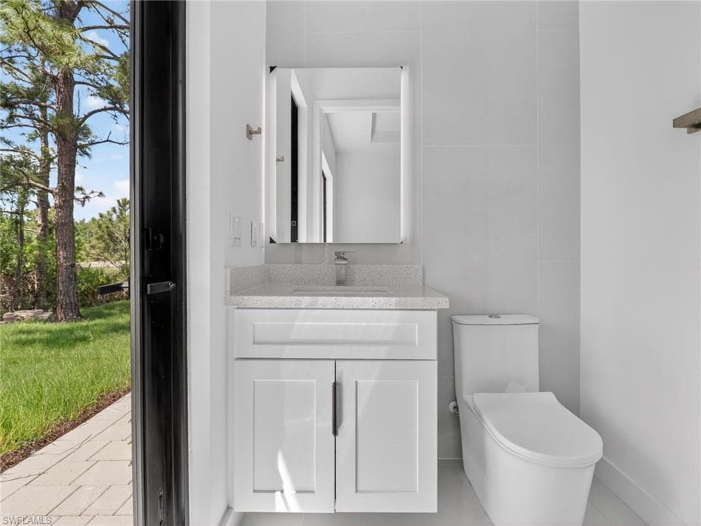 This bathroom features a contemporary white vanity with a light-colored countertop and a modern toilet