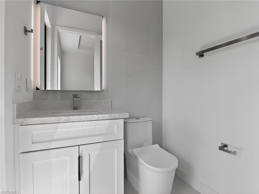 Modern bathroom vanity with a light speckled countertop, an integrated sink, and an illuminated mirror