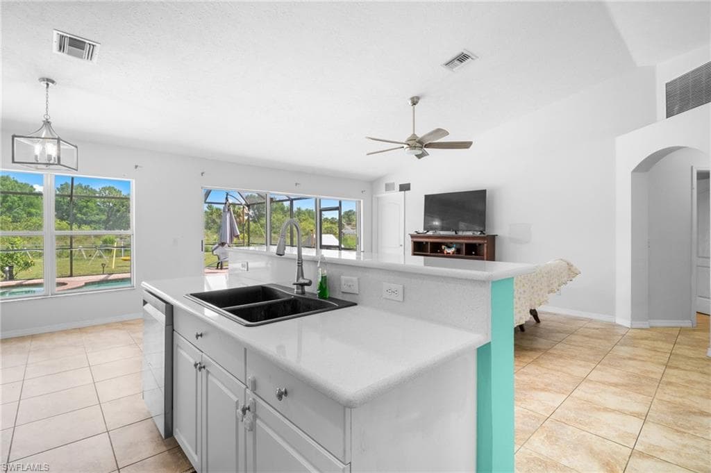Kitchen with a sink, stainless steel dishwasher, light countertops, and ceiling fan
