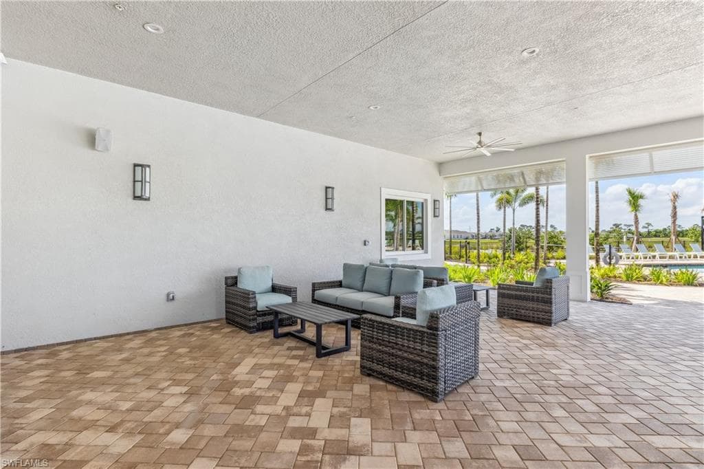 The property features an expansive covered patio area with a paver floor, recessed lighting, and a ceiling fan