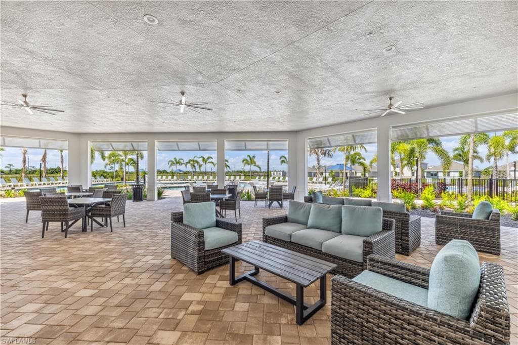 Covered outdoor patio featuring a variety of seating arrangements, ceiling fans, and a paver floor