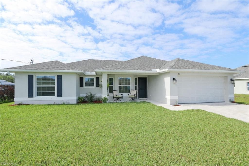 This property features a well-maintained lawn, a spacious driveway, and an attached garage