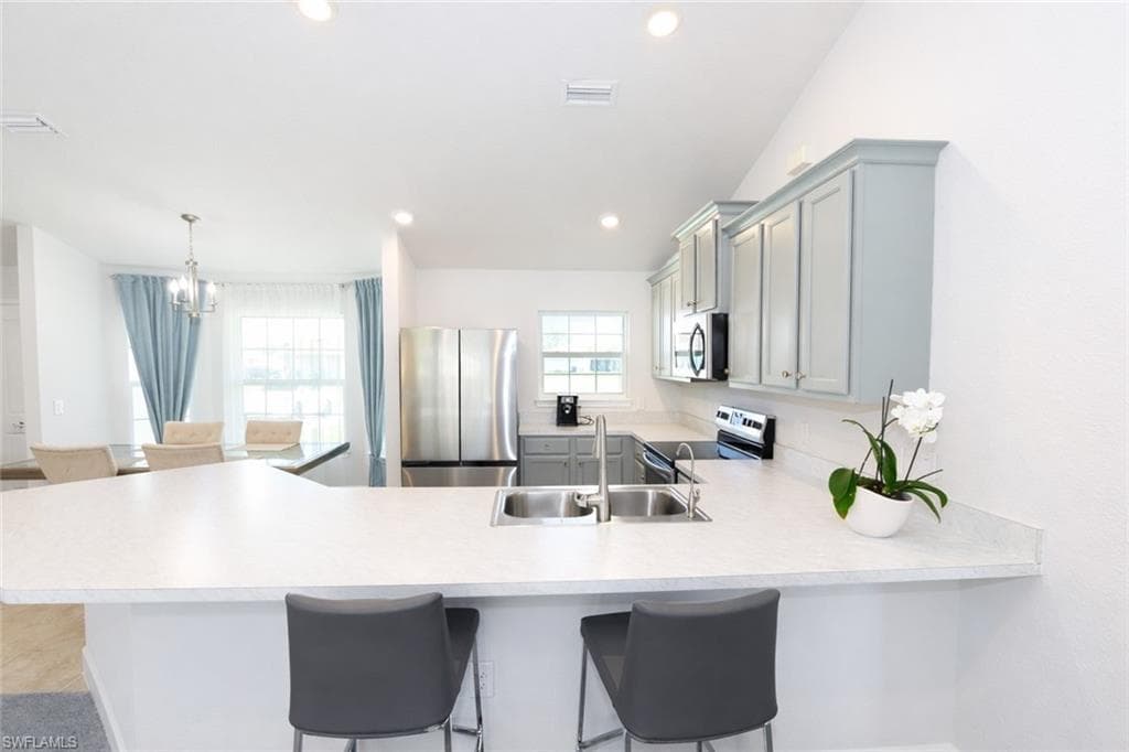 The kitchen features light-toned countertops, a double basin sink, and stainless steel appliances