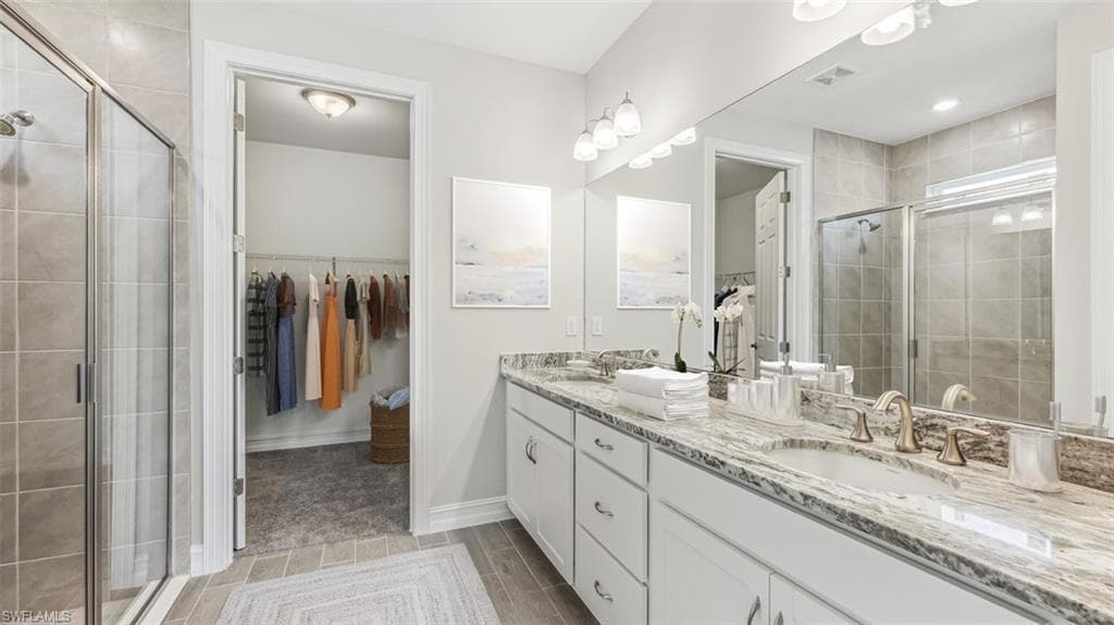 This image is virtually staged. Full bathroom featuring a spacious closet, double vanity, and a shower stall